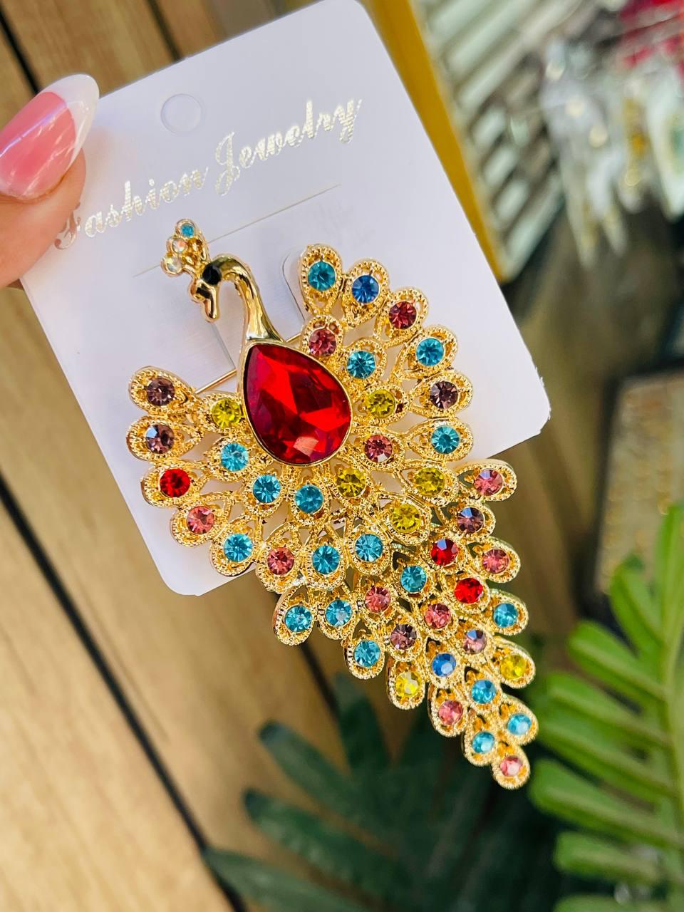 Gold peacock brooch with multicolor crystals and red teardrop gemstone